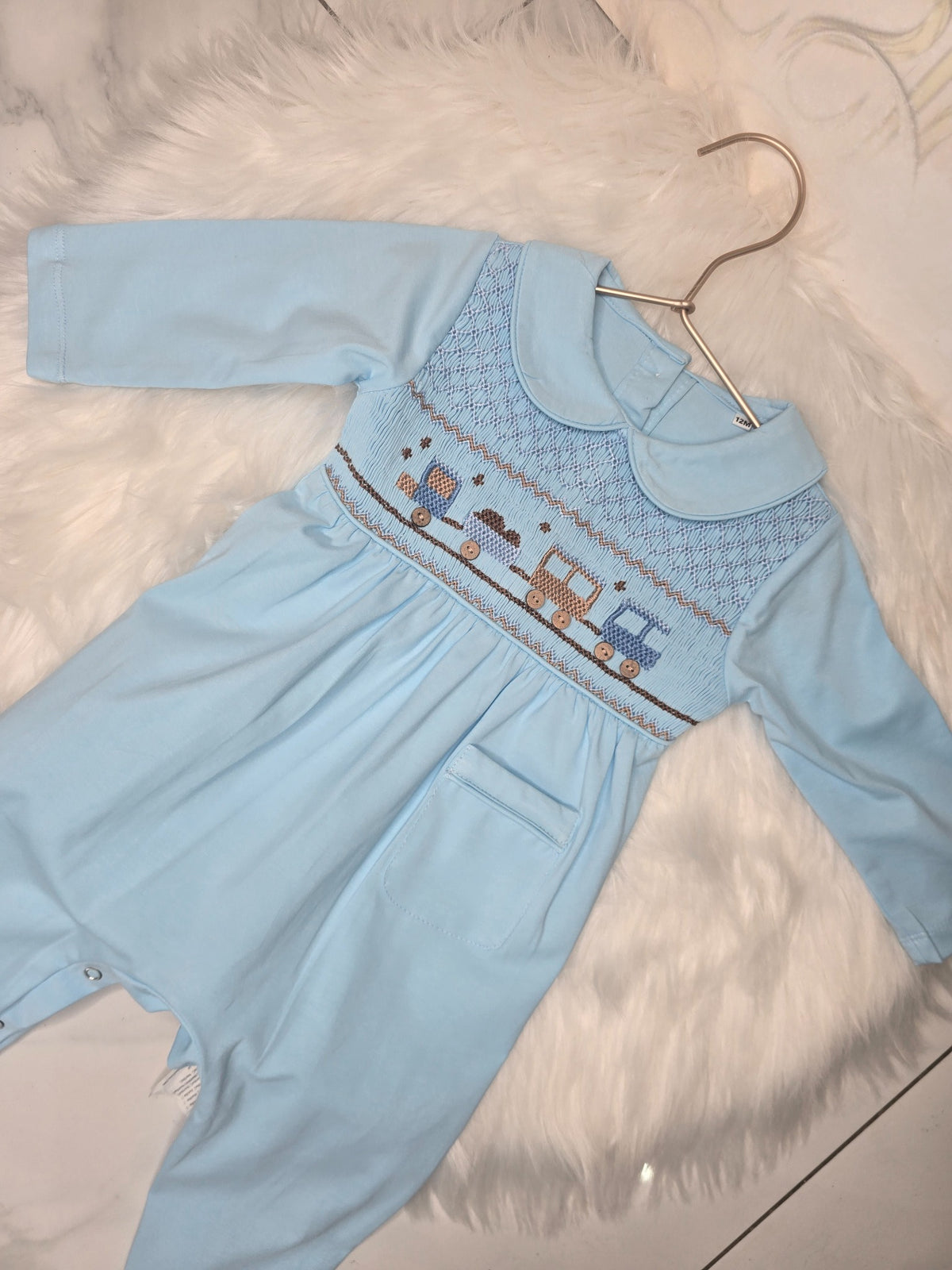 Baby blue long sleeve smocked romper with train embroidery and Peter Pan collar