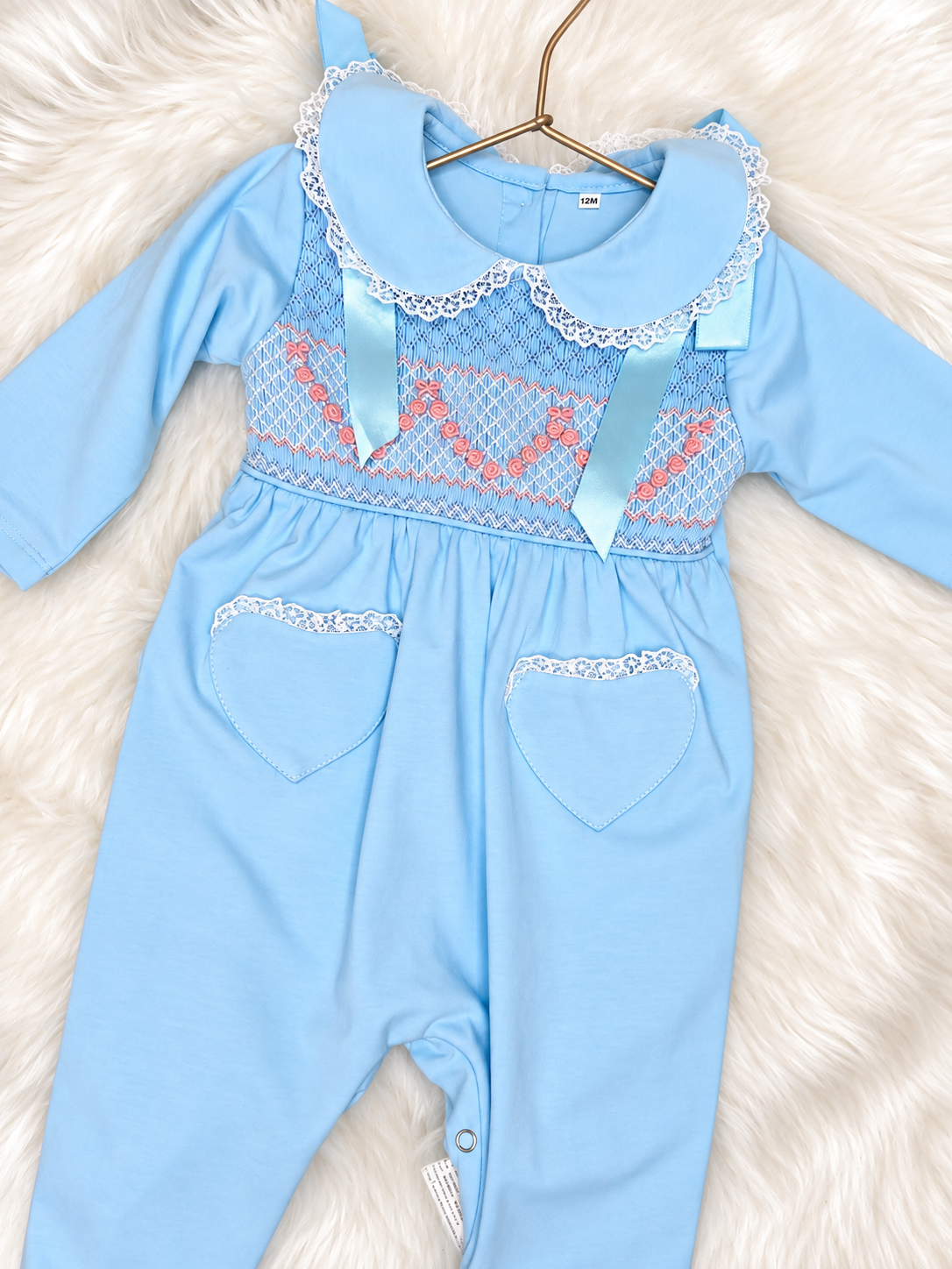 Pale blue baby girls smocked romper with lace collar, embroidered bodice, ribbon details and heart pockets